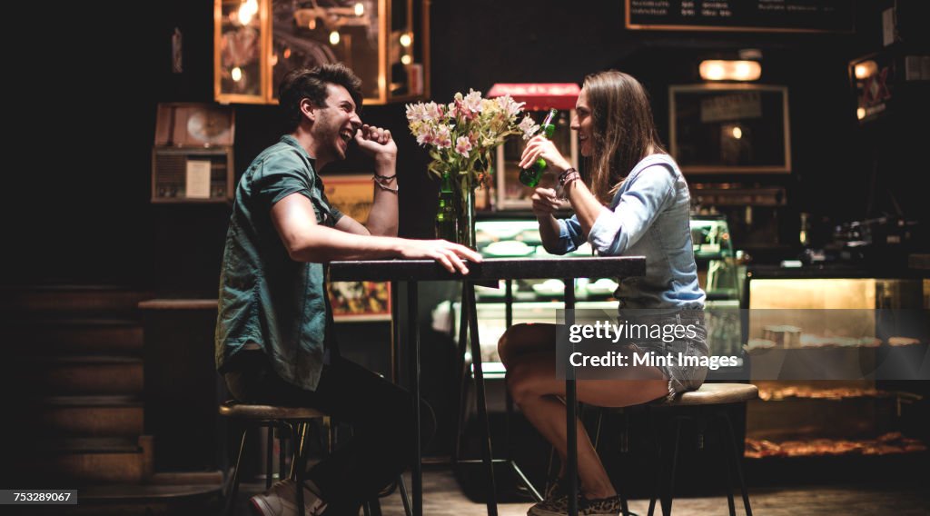 Two young people sitting at a table in a bar.