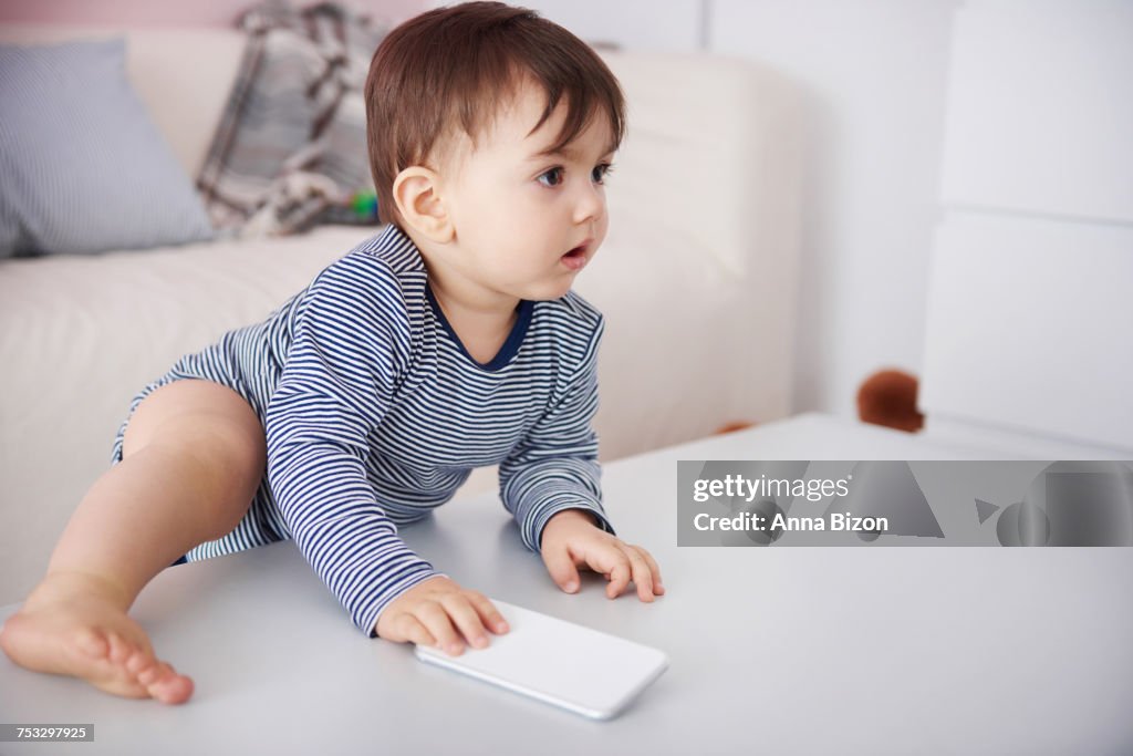 Little baby climbing with cell phone on the table. Debica, Poland