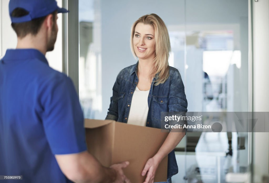 Woman getting a parcel from delivery man. Debica, Poland
