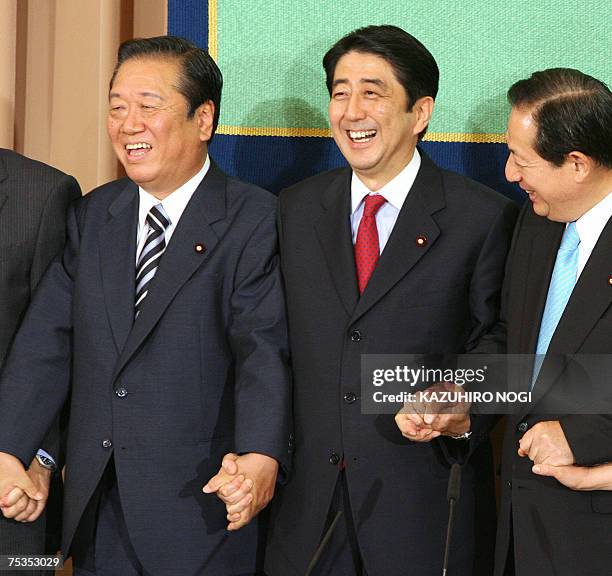 Japanese Prime Minister and ruling Liberal Democratic Party President Shinzo Abe shakes hands with coalition party New Komeito leader Akihiro Ota and...