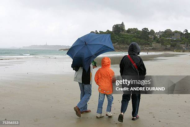 Des touristes marchent sur la plage, le 10 juillet 2007 a Dinard. Meme s'ils font grise mine apres des mois de mai et juin maussades, les...