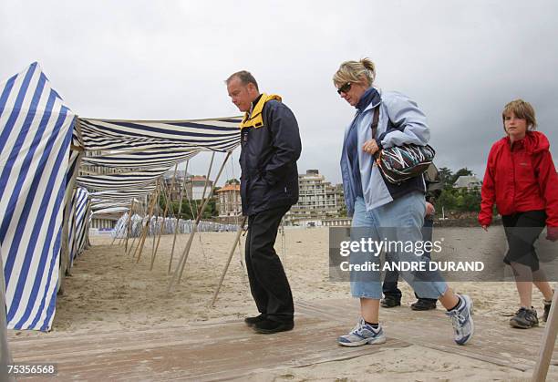 Des touristes marchent sur la plage, le 10 juillet 2007 a Dinard. Meme s'ils font grise mine apres des mois de mai et juin maussades, les...