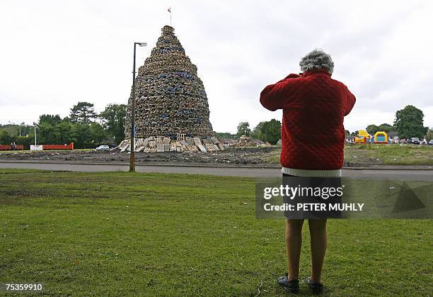 Antrim, UNITED KINGDOM: A resident takes a photograph of the Ballycraigy estate bonfire pyre in Ballycraigy estate in Antirm, Northern Ireland, 11...