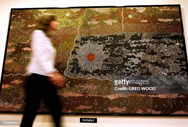 Sotheby's employee walks past a painting by Aboriginal artist Clifford Possum Tjapaltjarri titled "Warlugulong 1977", in Sydney, 12 July 2007....
