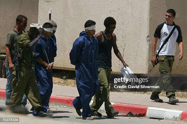 Israeli soldiers escort handcuffed and blindfolded Palestinians to questioning in an army base July 12, 2007 near Kibbutz Nahal Oz on the border with...