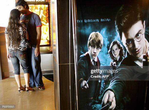 An Indian couple stand beside a poster advertising the latest film featuting the character Harry Potter at a cinema in Mumbai, 12 July 2007. Movie...