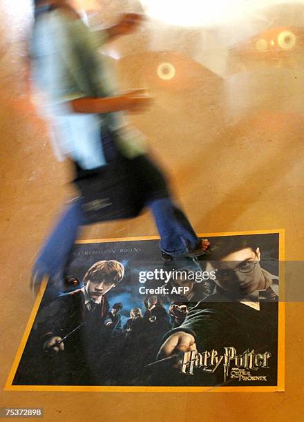 An Indian woman walks across a poster advertising the latest film featuring the character Harry Potter at a cinema in Mumbai, 12 July 2007. Movie...