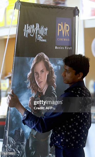 An Indian cinema employee carries a poster advertising the latest film featuring the character Harry Potter at a cinema in Mumbai, 12 July 2007....