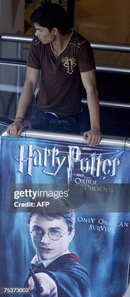 An Indian cinema employee stands beside a poster advertising the latest film featuring the character Harry Potter at a cinema in Mumbai, 12 July...