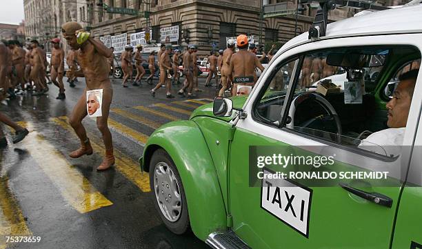 Taxi driver looks at naked peasants, members of the "400 Pueblos" mouvement protesting in Mexico City 11 July 2007, against the dispossession of land...