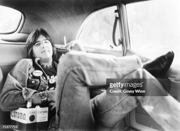 Singer/songwriter Gram Parsons poses for a portrait session wearing a t-shirt advertising his band Flying Burrito Bros. In the backseat of a Cadillac...