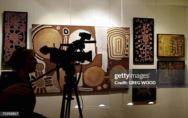 Woman films near Aboriginal artwork at Sotheby's Auction House, in Sydney, 12 July 2007. A painting by Clifford Possum Tjapaltjarri titled...