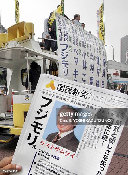 An election campaign staff of the New People's Party holds a party leaflet which carries a portrait of former Peruvian President Alberto Fujimori who...