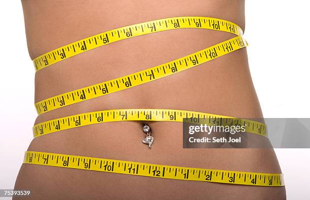 woman with tape measure around abdomen with belly button piercing, mid section, close-up - inch stock pictures, royalty-free photos & images