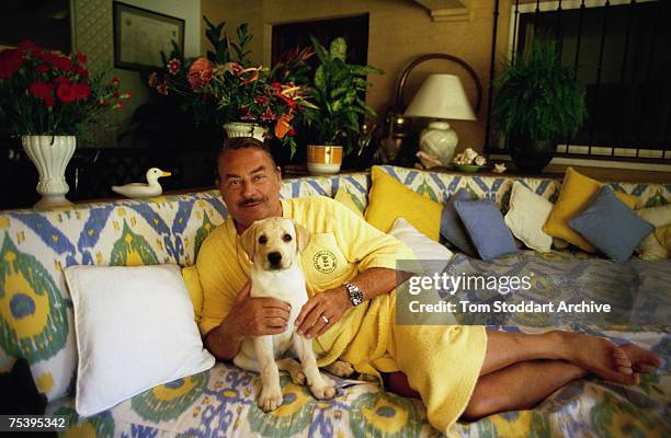 Prince Alfonso of Hohenlohe-Langenburg at home with his labrador puppy Camello, 1989. He is wearing a towelling robe from the Marbella Club Hotel,...