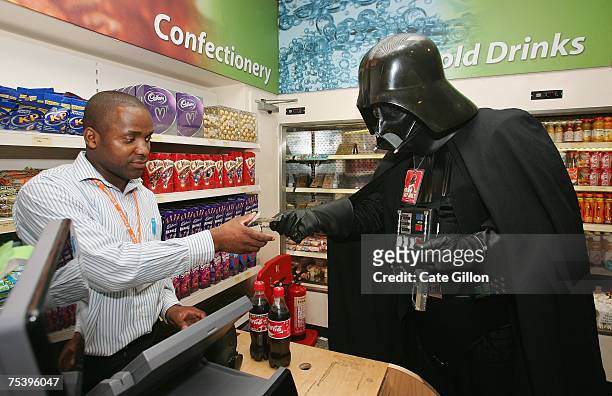Man dressed in Darth Vader costume buys a drink from a refreshment shop at the Celebration Europe Exhibition in Excel Centre on July 13, 2007 in...
