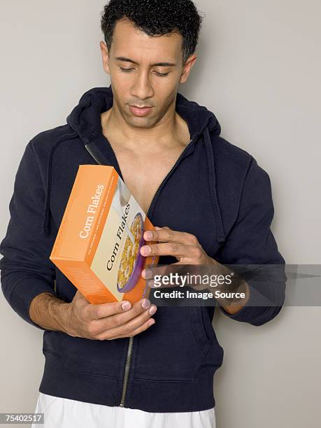 man looking at cereal packet - cereal box stockfoto's en -beelden