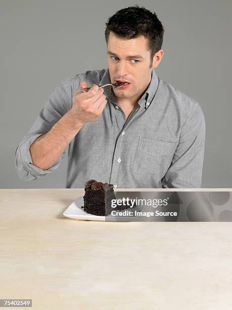 uomo che mangia una torta al cioccolato - chocolate cake foto e immagini stock