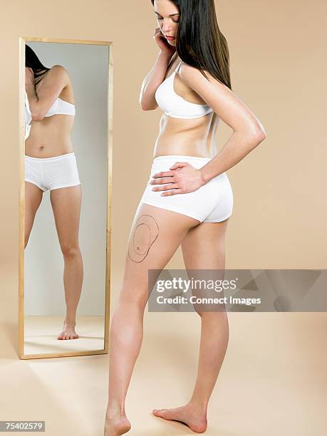 woman looking at mark on her leg - plastic surgery body stock pictures, royalty-free photos & images