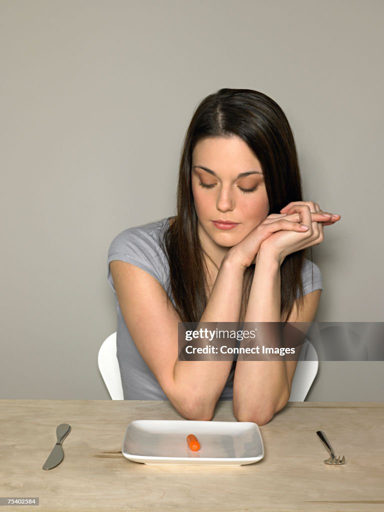 Young woman with carrot on a plate