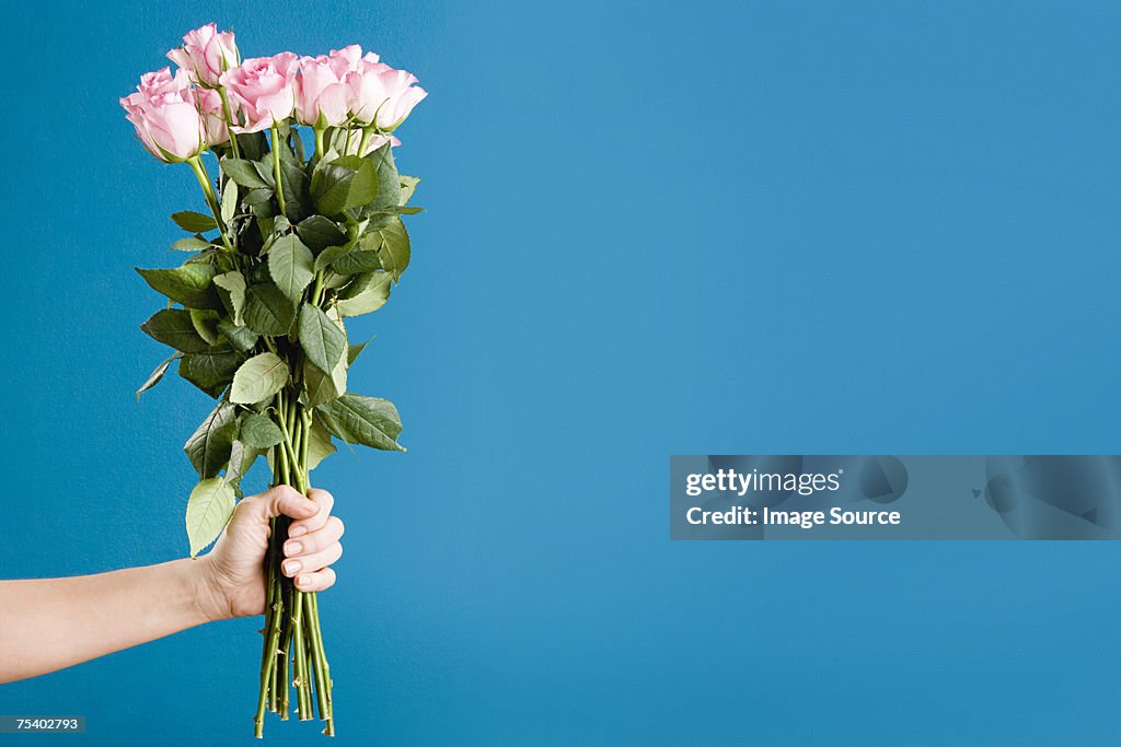 Person hält einen Strauß Rosen