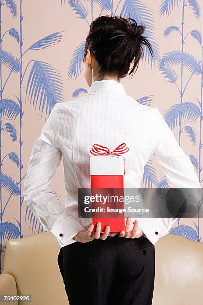 jeune femme avec un cadeau derrière son dos - hands behind back stock photos et images de collection