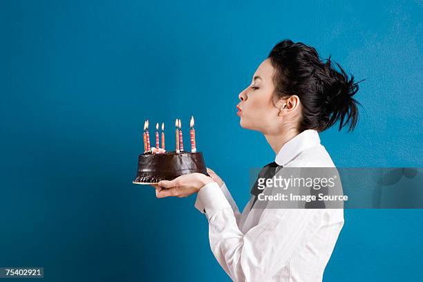 junge frau blasen out geburtstag kerzen - woman holding cake stock-fotos und bilder
