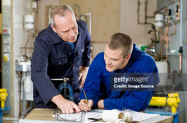 plumber and apprentice - showing stock pictures, royalty-free photos & images