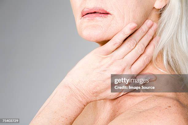 woman touching her neck - lentigo stockfoto's en -beelden