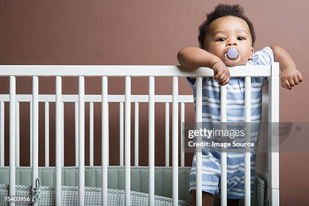 baby boy standing in cot - jongensbaby's stockfoto's en -beelden
