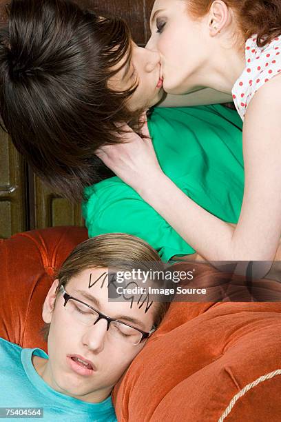 couple kissing near sleeping boy - girl of desire stock pictures, royalty-free photos & images