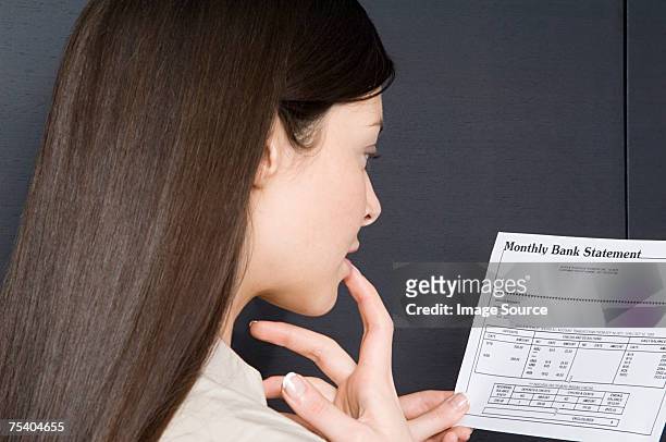 woman looking at bank statement - bank statement stock-fotos und bilder