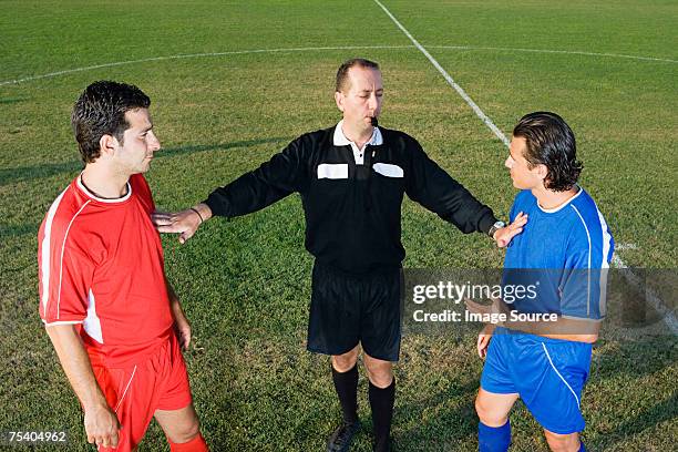 schiedsrichter stoppen zwei spieler - schiedsrichter stock-fotos und bilder