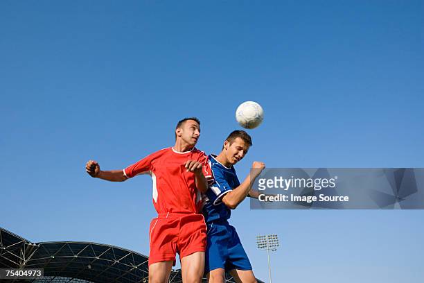 footballers heading football - two guys playing soccer stockfoto's en -beelden