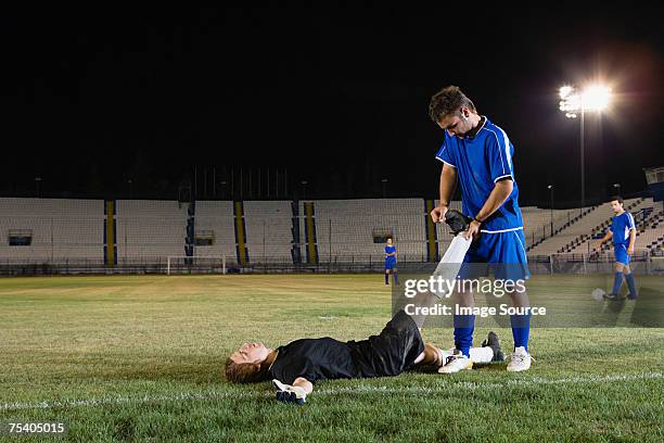 footballer helping goalkeeper - injured football player stock pictures, royalty-free photos & images