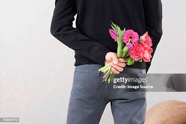 man holding flowers behind back - hands behind back stock pictures, royalty-free photos & images