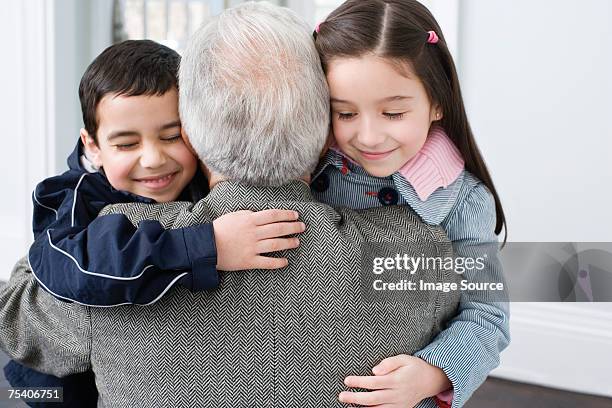 brother and sister hugging grandfather - child winter coat stock pictures, royalty-free photos & images