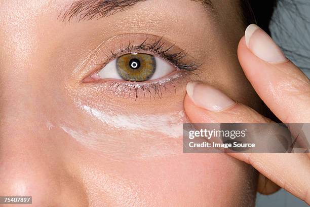 donna applica moisturiser - human eye foto e immagini stock