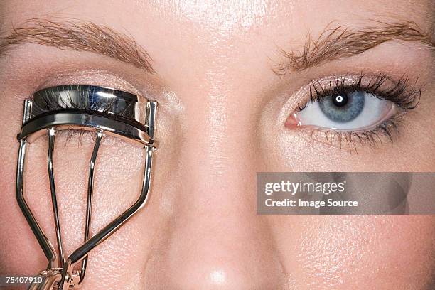 woman using eyelash curlers - wimperkruller stockfoto's en -beelden