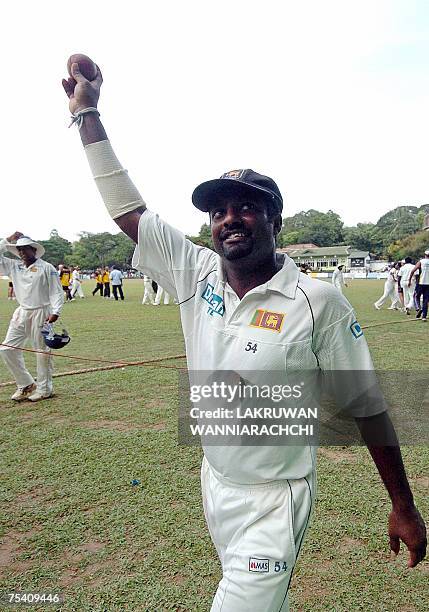 Sri Lankan cricketer Muttiah Muralitharan celebrates with the ball with which he took his 700th Test wicket during the Test match against Bangladesh...