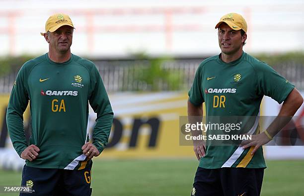 Australian football team coach Grahim Arnold and defender Lucas Neill watch teammates during a training session in Bangkok, 14 July 2007. Under-siege...