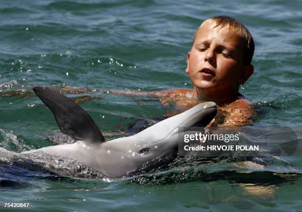 Krilo Jesenice, CROATIA: A child plays with baby dolphin in front of the beach near the southern Croatian Adriatic town of Krilo Jesenice, 15 July...