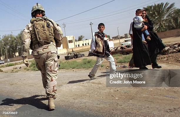 Iraqi pedestrians pass by as American Special Forces guard a meeting of tribal sheikhs July 15, 2007 in Kanan in the Diyala province of Iraq....