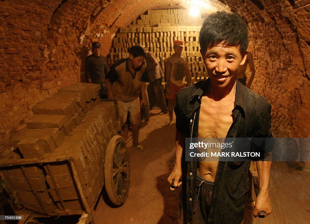 Chinese workers stack bricks inside a ki...