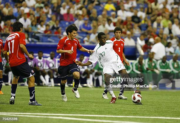 Akeem Latifu of Nigeria splits between Gary Medel and Mauricio Isla of Chile while trying to carry the ball deep into the offensive zone during the...