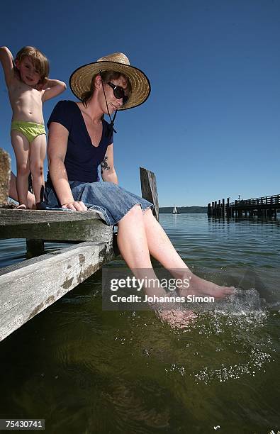 Young woman cools her feet sitting on a boardwalk at the Ammersee Lake on July 16, 2007 in Diessen am Ammersee, Germany. The heatwave is expected to...