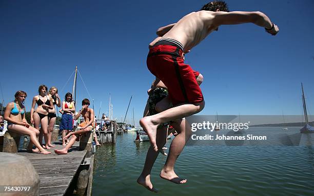 Young people jump from a boardwalk into the cool water of the Ammersee Lake on July 16, 2007 in Diessen am Ammersee, Germany. The heatwave is...