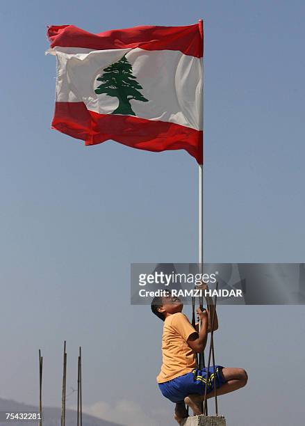 Lebanese boy hangs onto a Lebanese flag poll at the entrance of the Palestinian refugee camp of Nahr al-Bared, 16 July 2007. Two Lebanese soldiers...