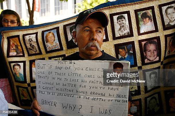 Frank Zamorro holds a placard with a picture of his son Dominic, who was allegedly abused by Father Michael Baker at age seven, during a press...