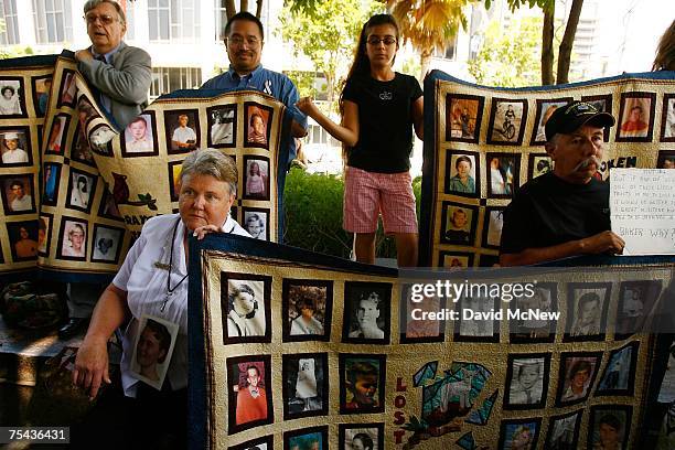 Alleged victims of sexual abuse at the hands of clergy hold quilts with photos of victims outside the Los Angeles County Courthouse where a record...